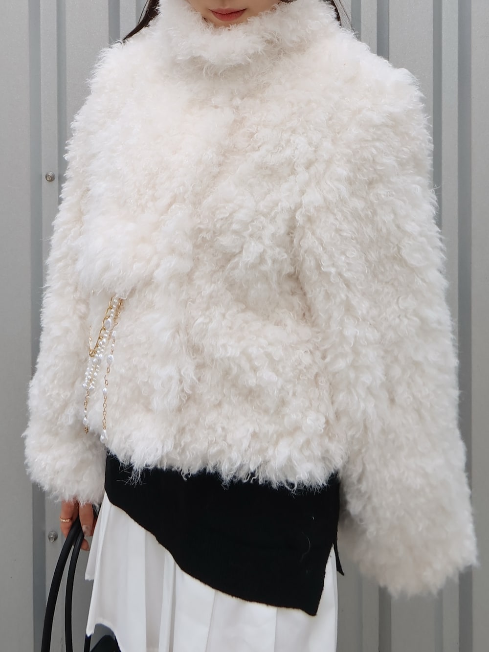 ブラック系のパンプス、ブラック系のハンドバッグ、ホワイト系のブルゾンを着用したレディースの秋コーディネートの4枚目の写真