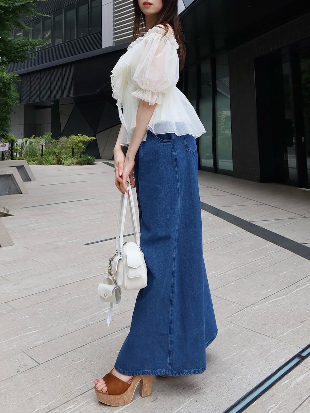 ホワイト系のボストンバッグ、ホワイト系のシャツ/ブラウス、ブルー系のデニムパンツを着用したレディースの夏コーディネートの2枚目の写真