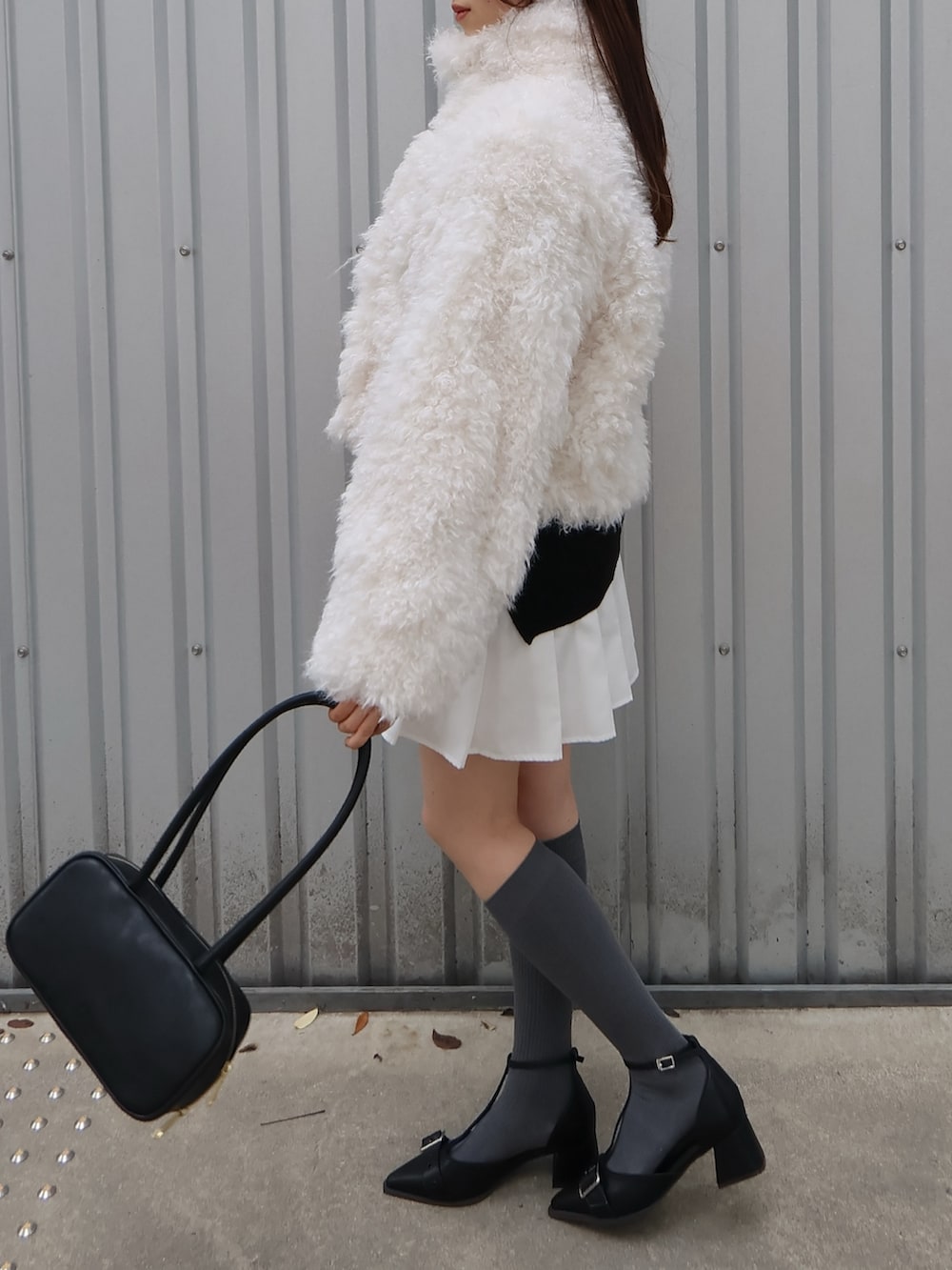 ブラック系のパンプス、ブラック系のハンドバッグ、ホワイト系のブルゾンを着用したレディースの秋コーディネートの2枚目の写真