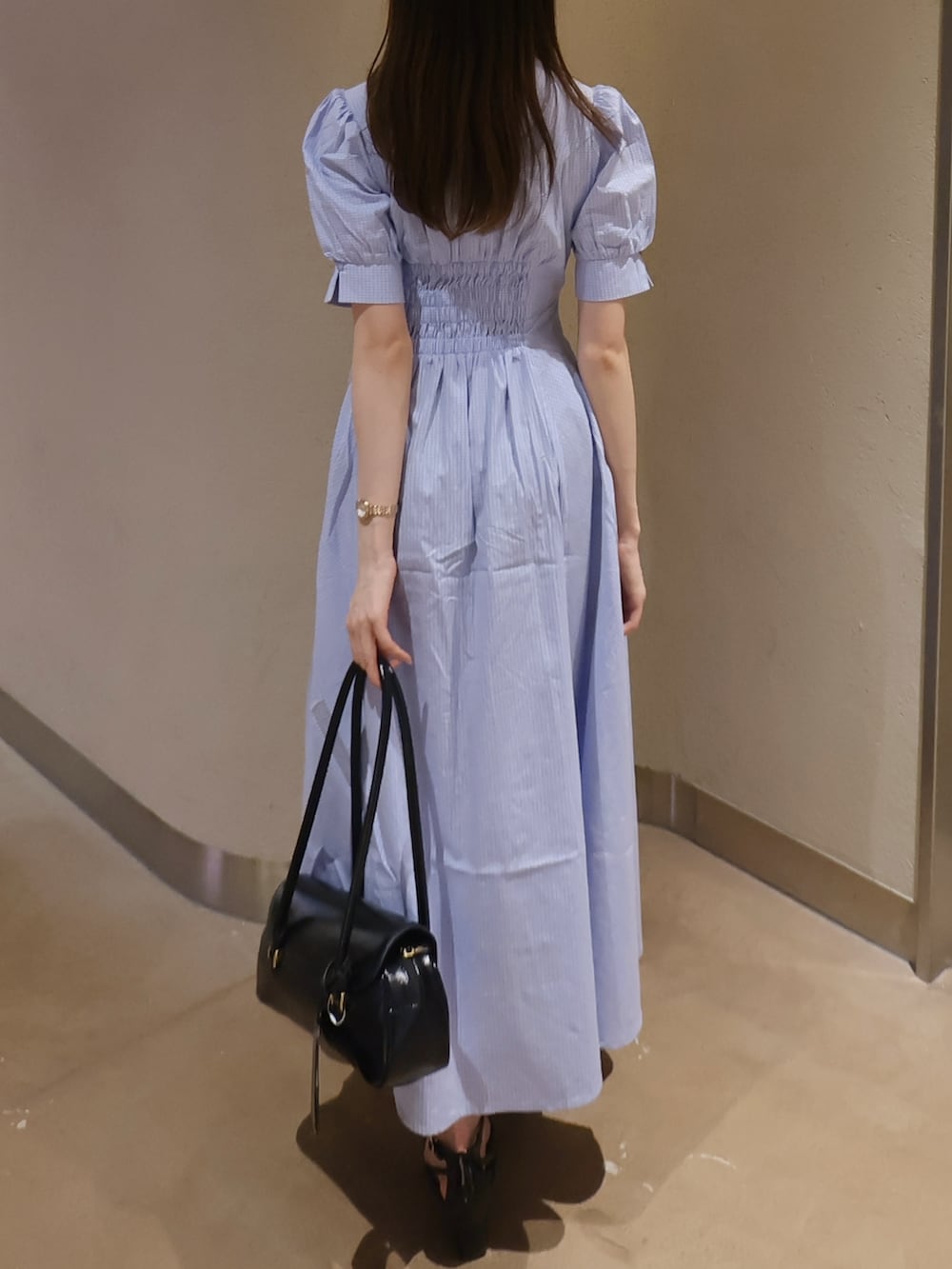 ブラック系のサンダル、ブラック系のハンドバッグ、ブルー系のワンピースを着用したレディースの夏コーディネートの3枚目の写真