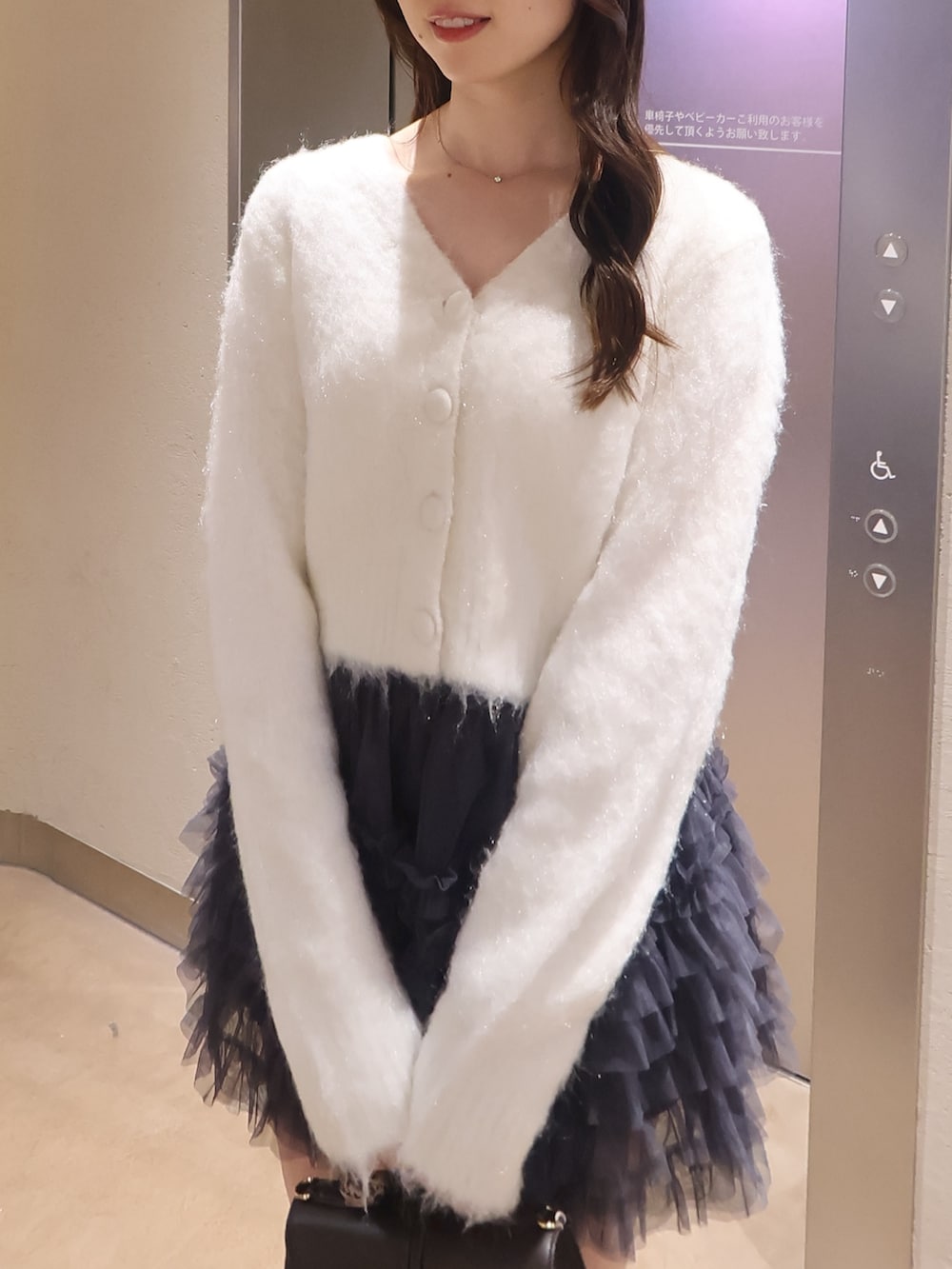 ホワイト系のカーディガン/ボレロ、グレー系のスカート、ブラウン系のショルダーバッグを着用したレディースの冬コーディネートの4枚目の写真