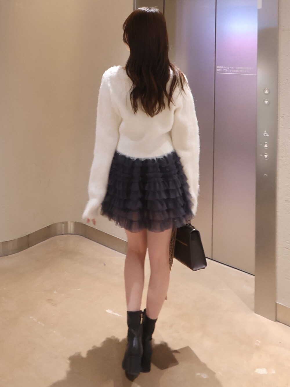 ホワイト系のカーディガン/ボレロ、グレー系のスカート、ブラウン系のショルダーバッグを着用したレディースの冬コーディネートの3枚目の写真