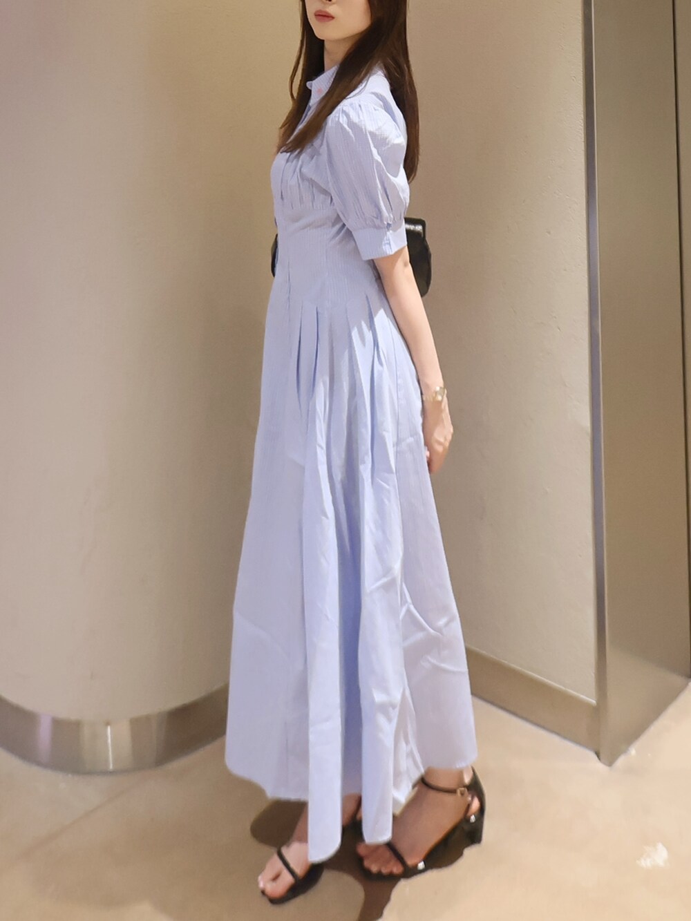 ブラック系のサンダル、ブラック系のハンドバッグ、ブルー系のワンピースを着用したレディースの夏コーディネートの2枚目の写真