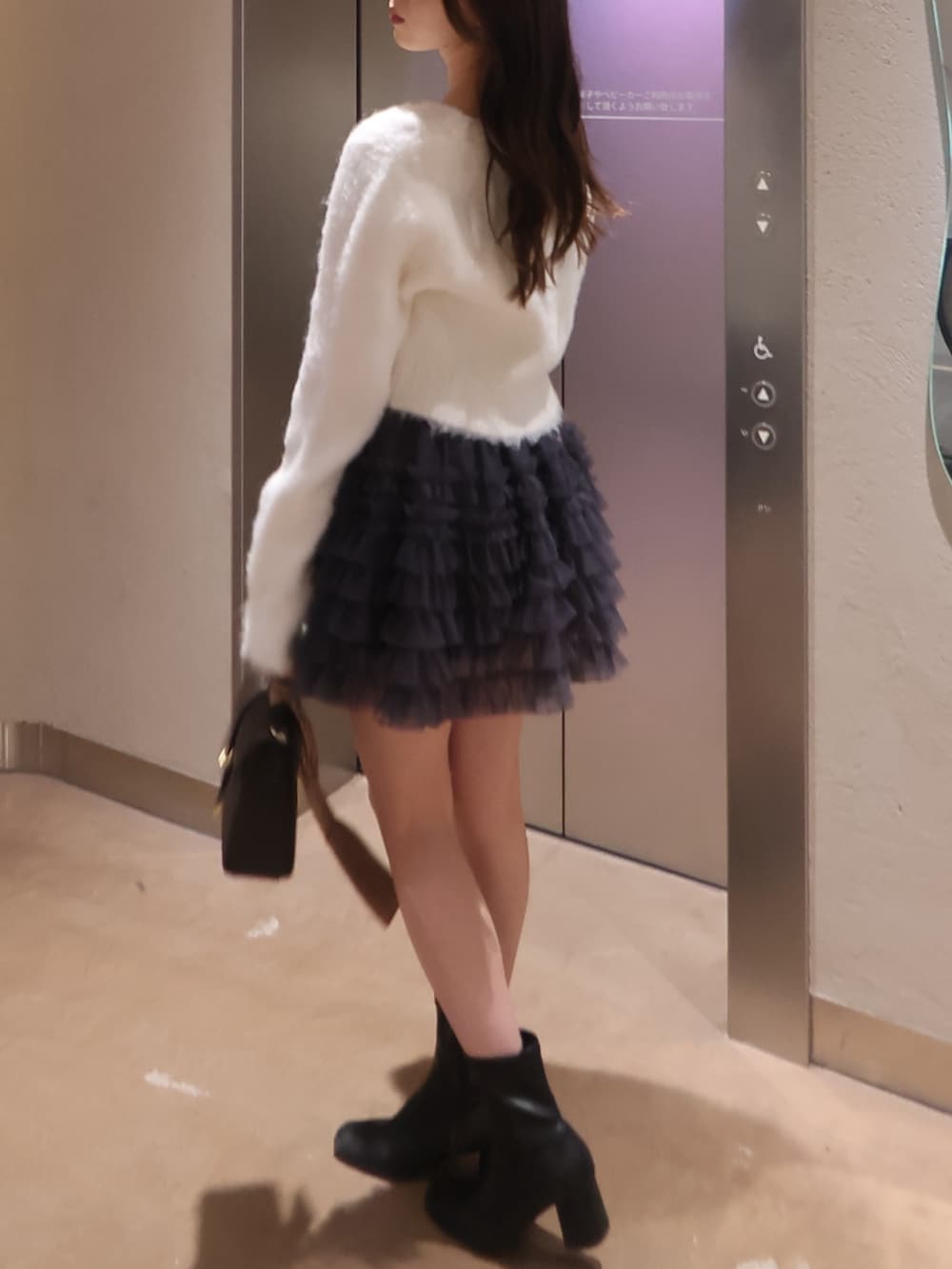 ホワイト系のカーディガン/ボレロ、グレー系のスカート、ブラウン系のショルダーバッグを着用したレディースの冬コーディネートの2枚目の写真