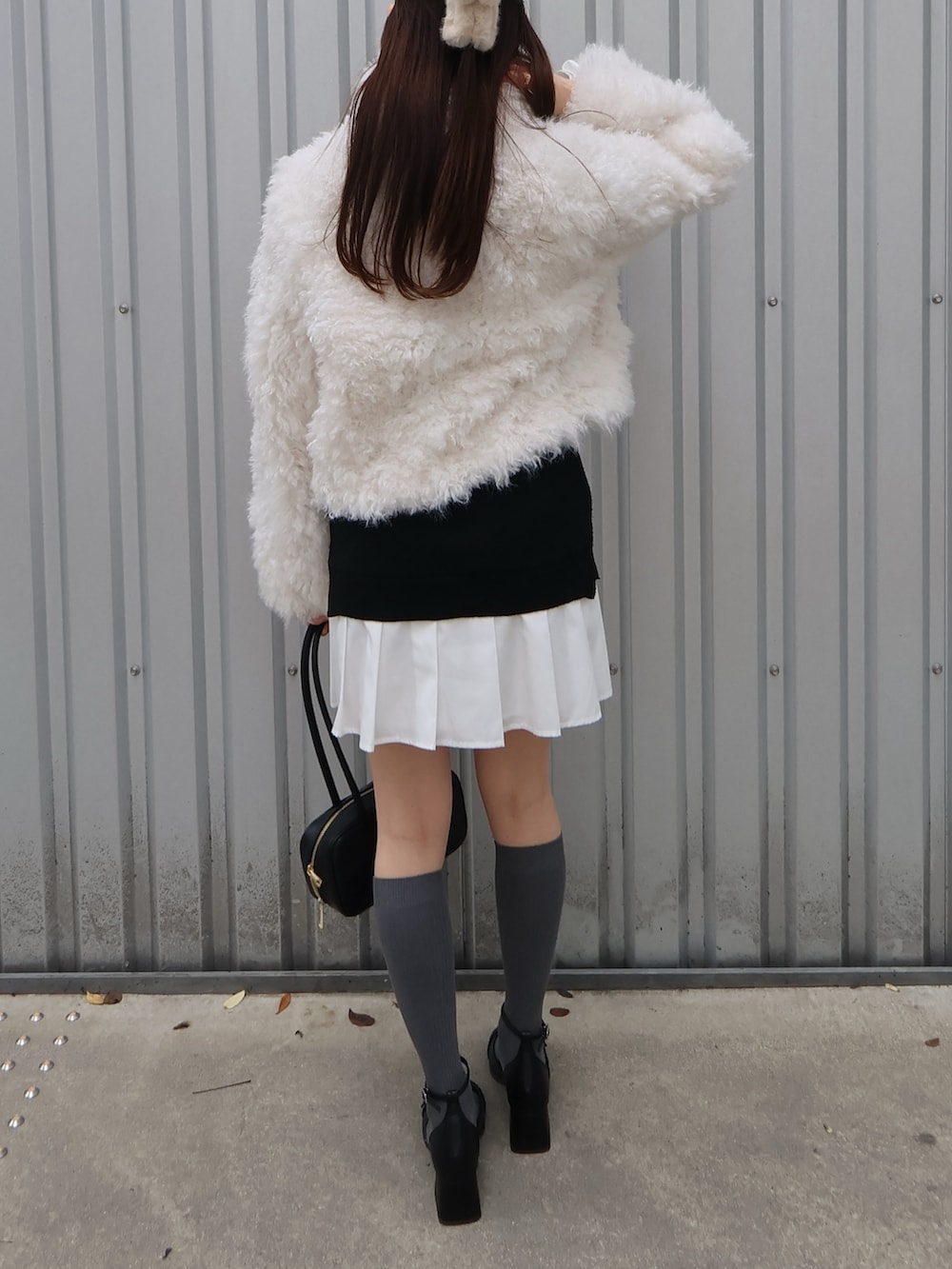 ブラック系のパンプス、ブラック系のハンドバッグ、ホワイト系のブルゾンを着用したレディースの秋コーディネートの3枚目の写真