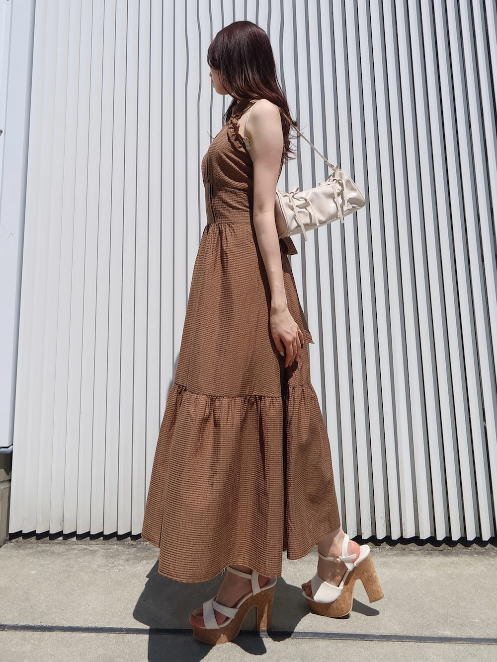 ブラウン系のワンピース、ホワイト系のサンダル、ホワイト系のハンドバッグを着用したレディースの夏コーディネートの2枚目の写真
