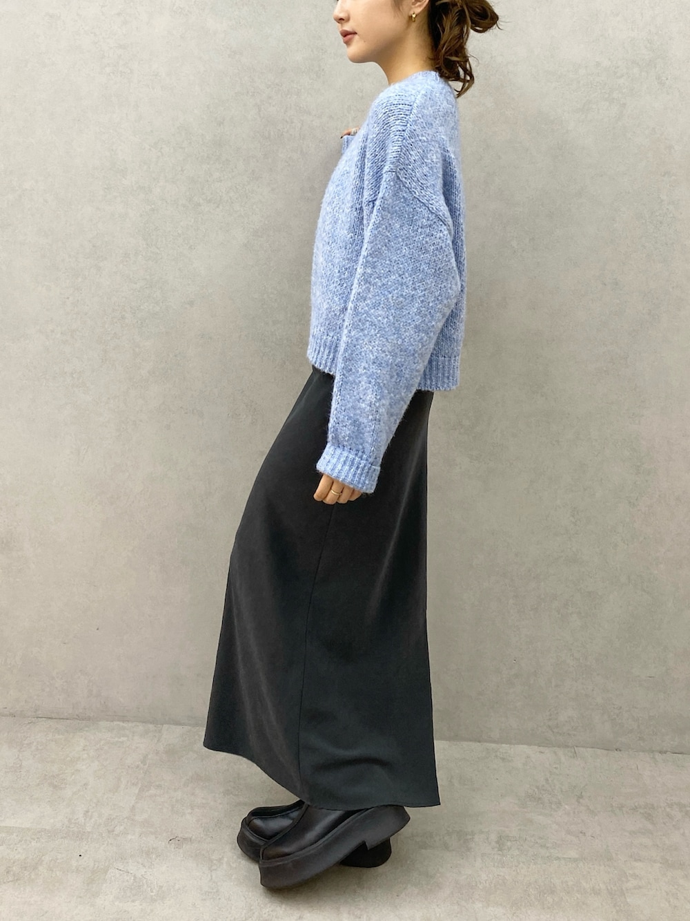 ブルー系のニット/セーター、グレー系のスカートを着用したレディースの秋コーディネートの2枚目の写真