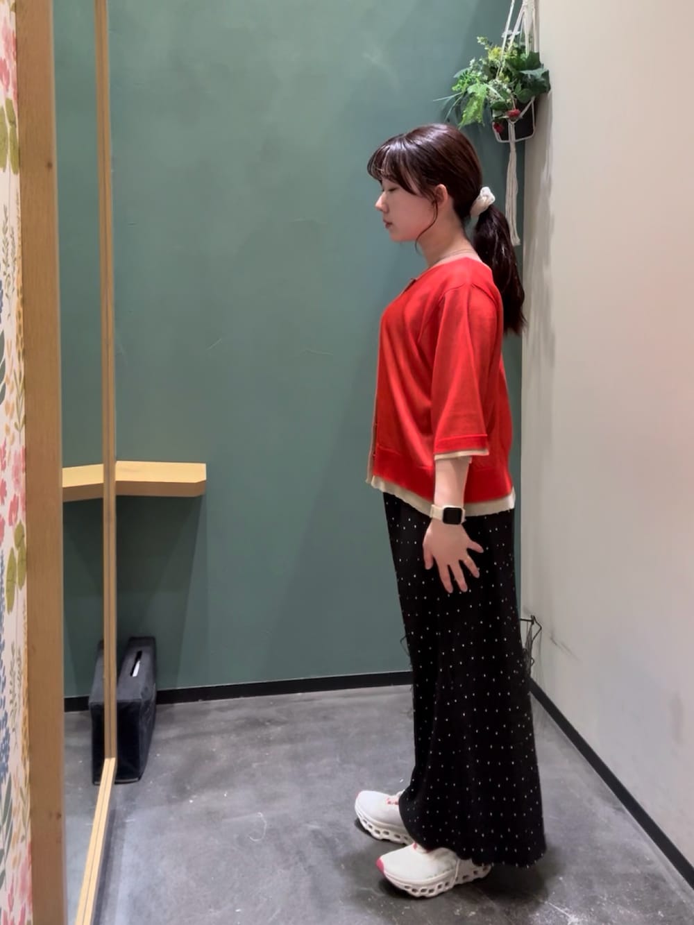 レッド系のカーディガン/ボレロ、ブラック系のスカート、ホワイト系のスニーカーを着用したレディースの秋コーディネートの2枚目の写真