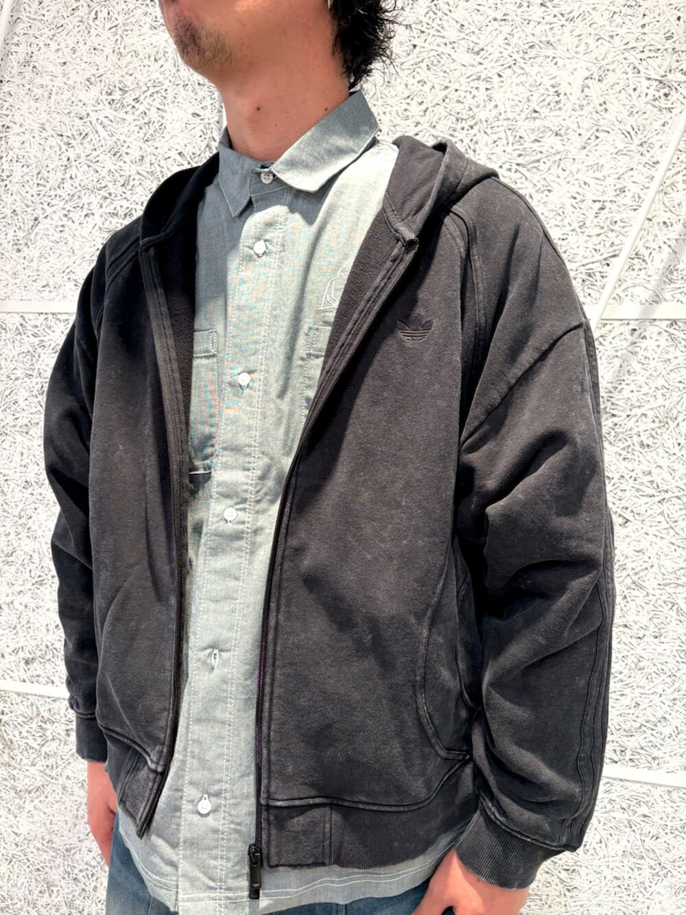 ブラック系のパーカー、グリーン系のトップス、ホワイト系のスニーカーを着用したメンズの冬コーディネートの3枚目の写真