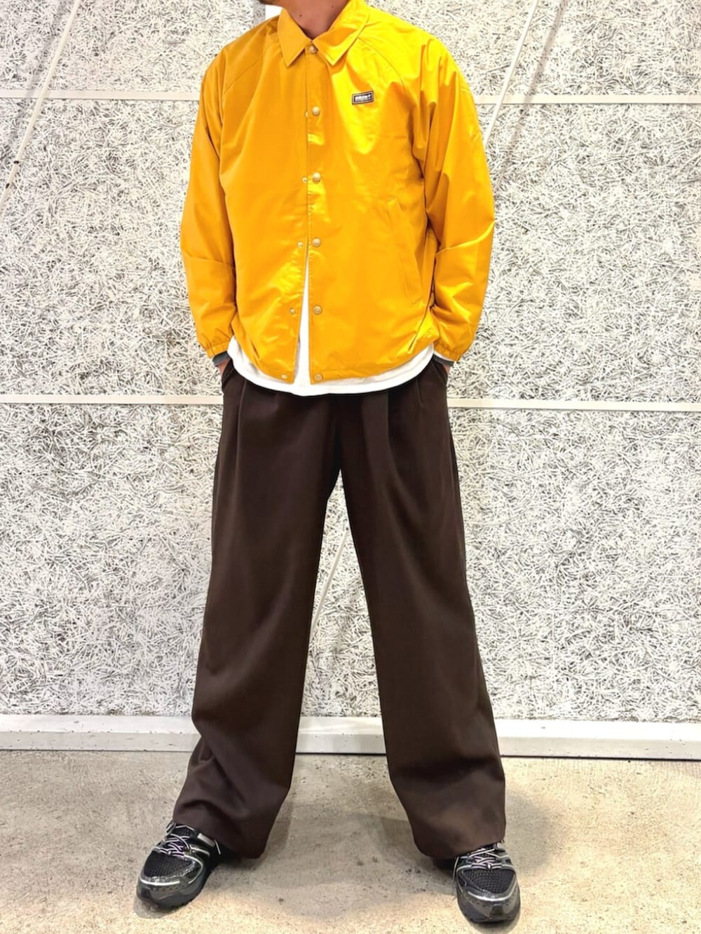 イエロー系のブルゾン、ブラック系のスニーカー、ブラック系のアクセサリーを着用したメンズの冬コーディネートの2枚目の写真