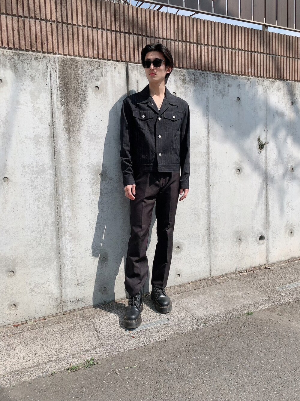 ブラック系のジャケット/アウター、ブラック系のブーツ、ブラック系のスラックスを着用したメンズの夏コーディネートの2枚目の写真