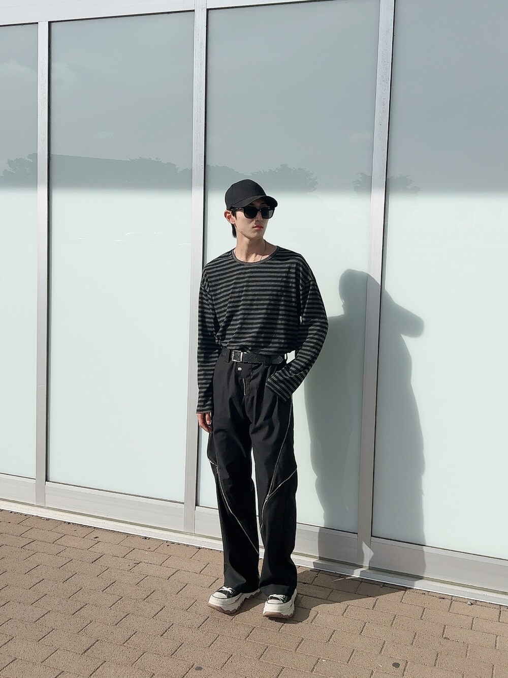 ブラック系のTシャツ/カットソー、ブラック系のスラックス、ブラック系のスニーカーを着用したメンズの夏コーディネートの2枚目の写真