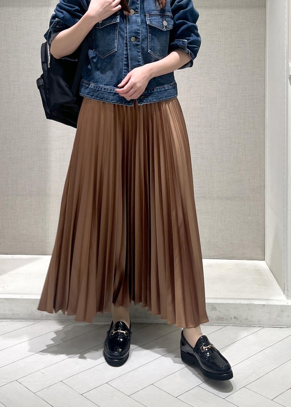 イエロー系のスカート、ブラック系のバックパック/リュック、ブラック系のローファーを着用したレディースの春コーディネートの6枚目の写真