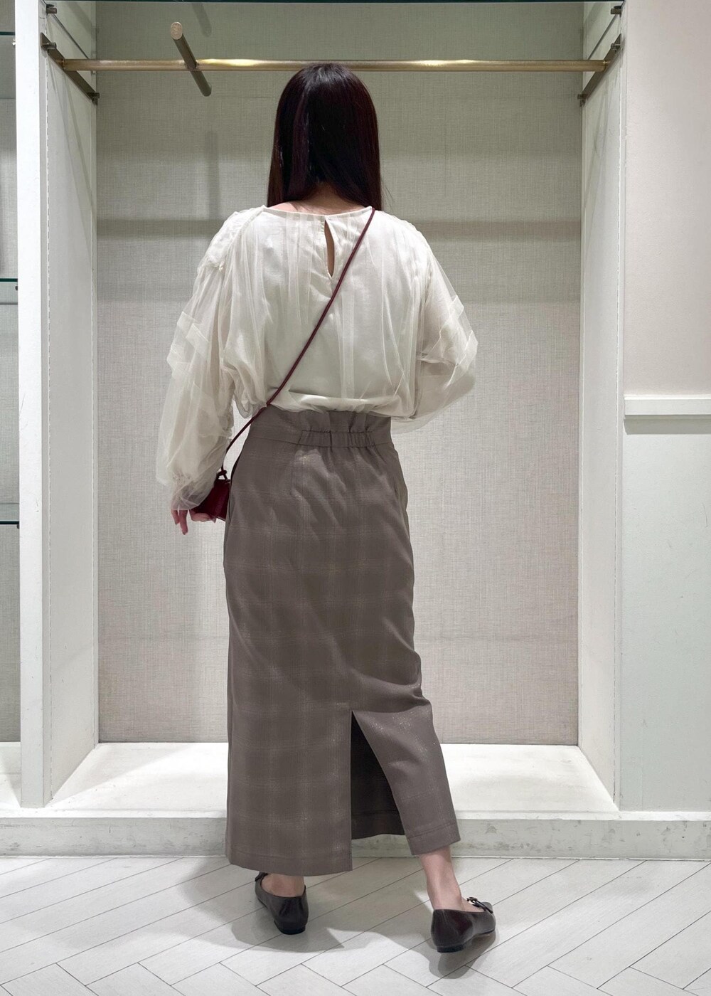 レッド系のショルダーバッグ、ブラウン系のパンプス、ベージュ系のスカートを着用したレディースの秋コーディネートの3枚目の写真