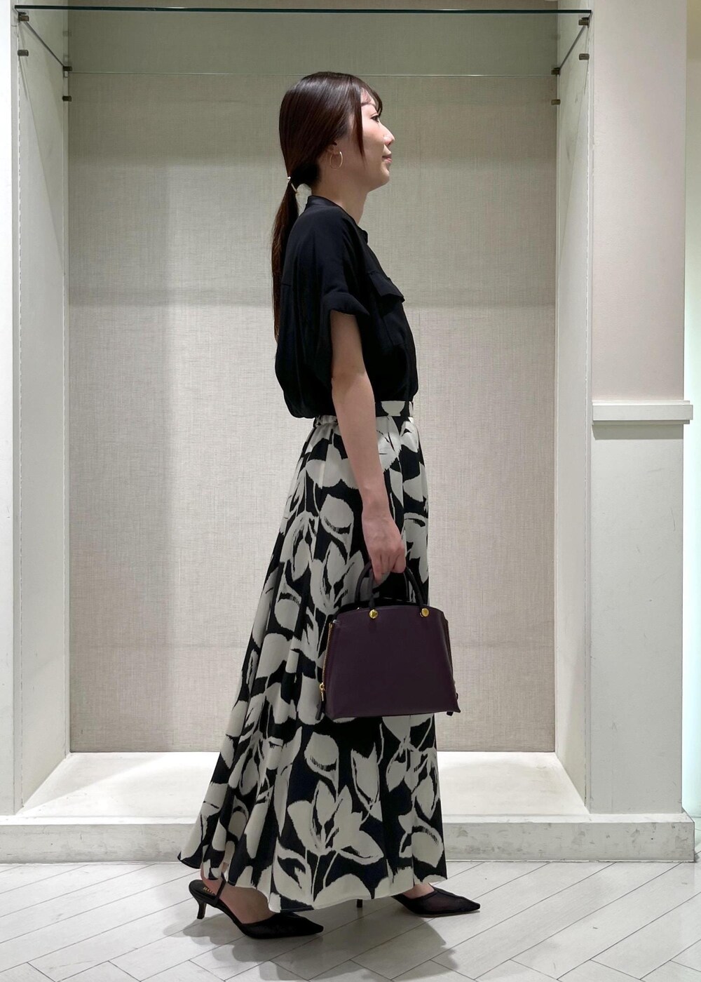 ブラック系のパンプス、パープル系のハンドバッグ、ブラック系のスカートを着用したレディースの秋コーディネートの2枚目の写真