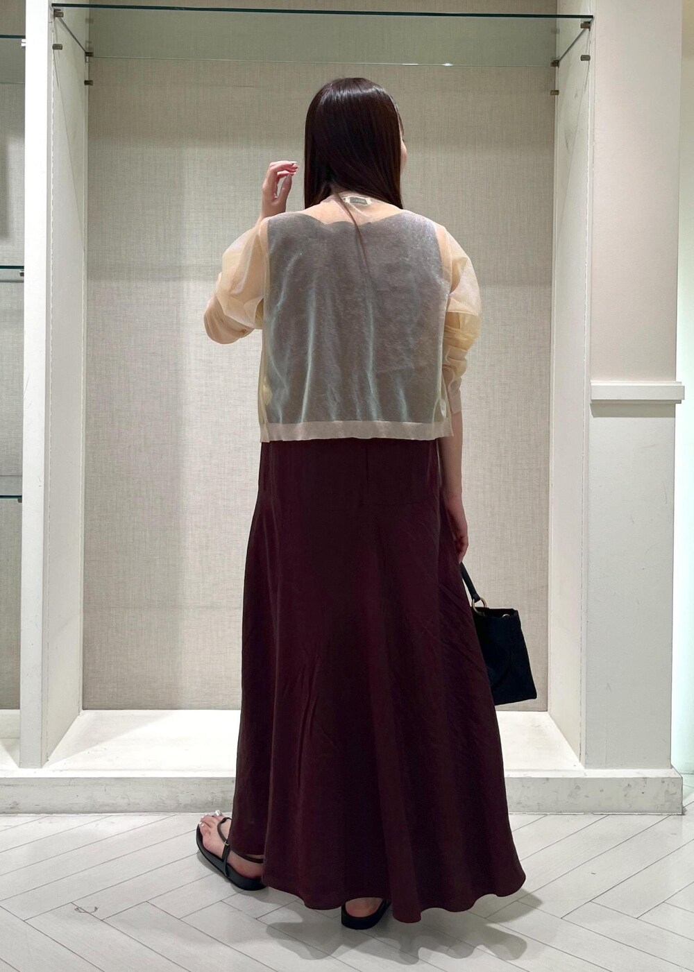 ブラック系のサンダル、ブラウン系のワンピース、ホワイト系のカーディガン/ボレロを着用したレディースの夏コーディネートの3枚目の写真