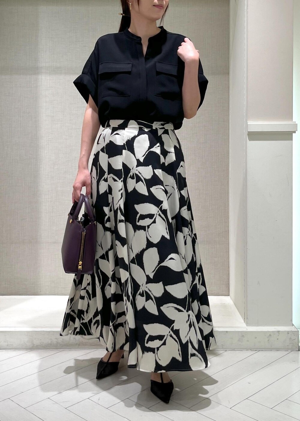 ブラック系のパンプス、パープル系のハンドバッグ、ブラック系のスカートを着用したレディースの秋コーディネートの4枚目の写真