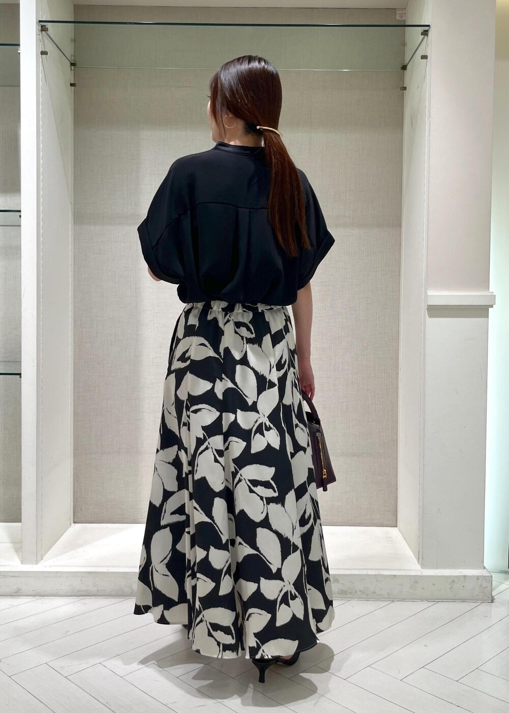 ブラック系のパンプス、パープル系のハンドバッグ、ブラック系のスカートを着用したレディースの秋コーディネートの3枚目の写真