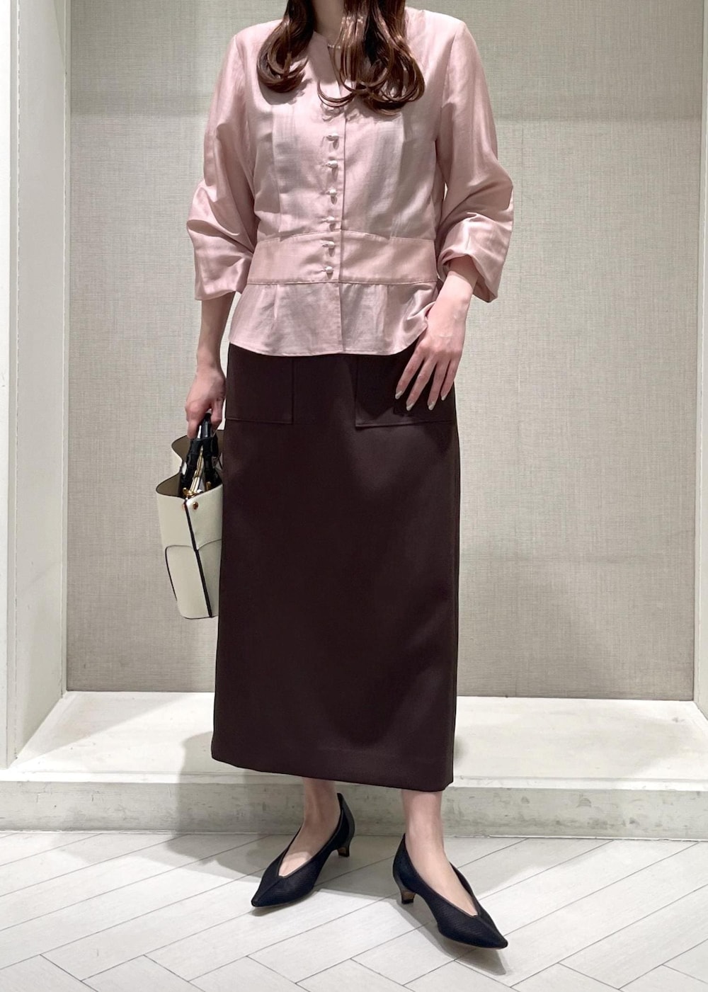 ブラック系のパンプス、ホワイト系のハンドバッグ、ブラウン系のスカートを着用したレディースの春コーディネートの4枚目の写真