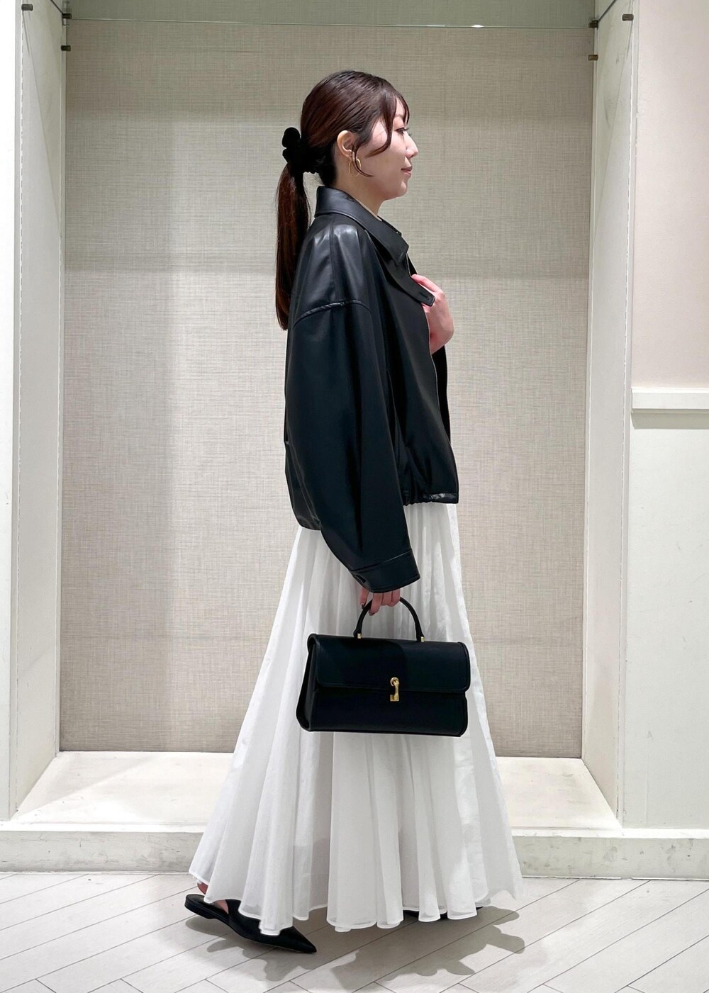ホワイト系のTシャツ/カットソー、ブラック系のパンプス、ホワイト系のスカートを着用したレディースの春コーディネートの2枚目の写真