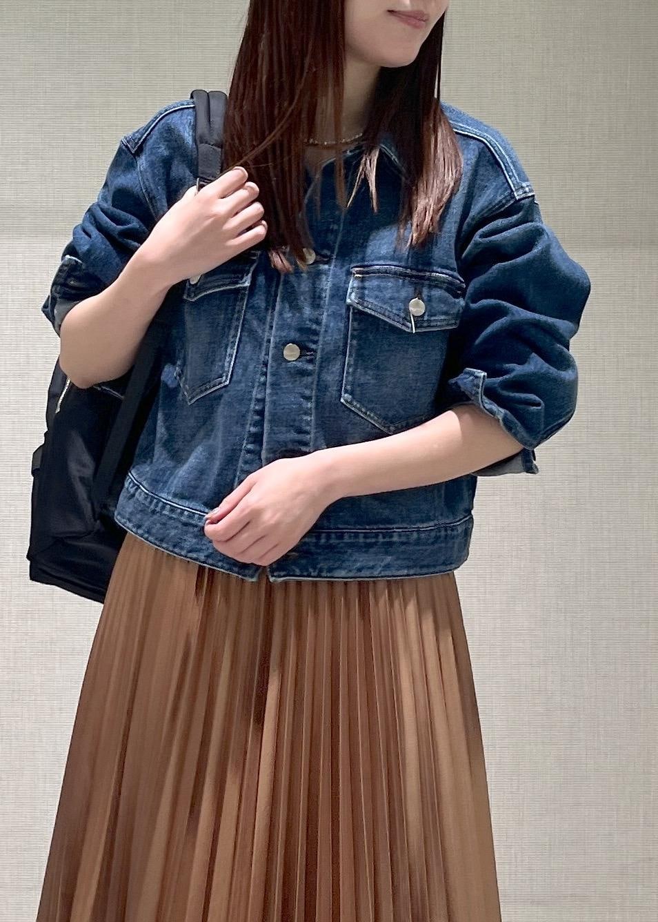 イエロー系のスカート、ブラック系のバックパック/リュック、ブラック系のローファーを着用したレディースの春コーディネートの4枚目の写真