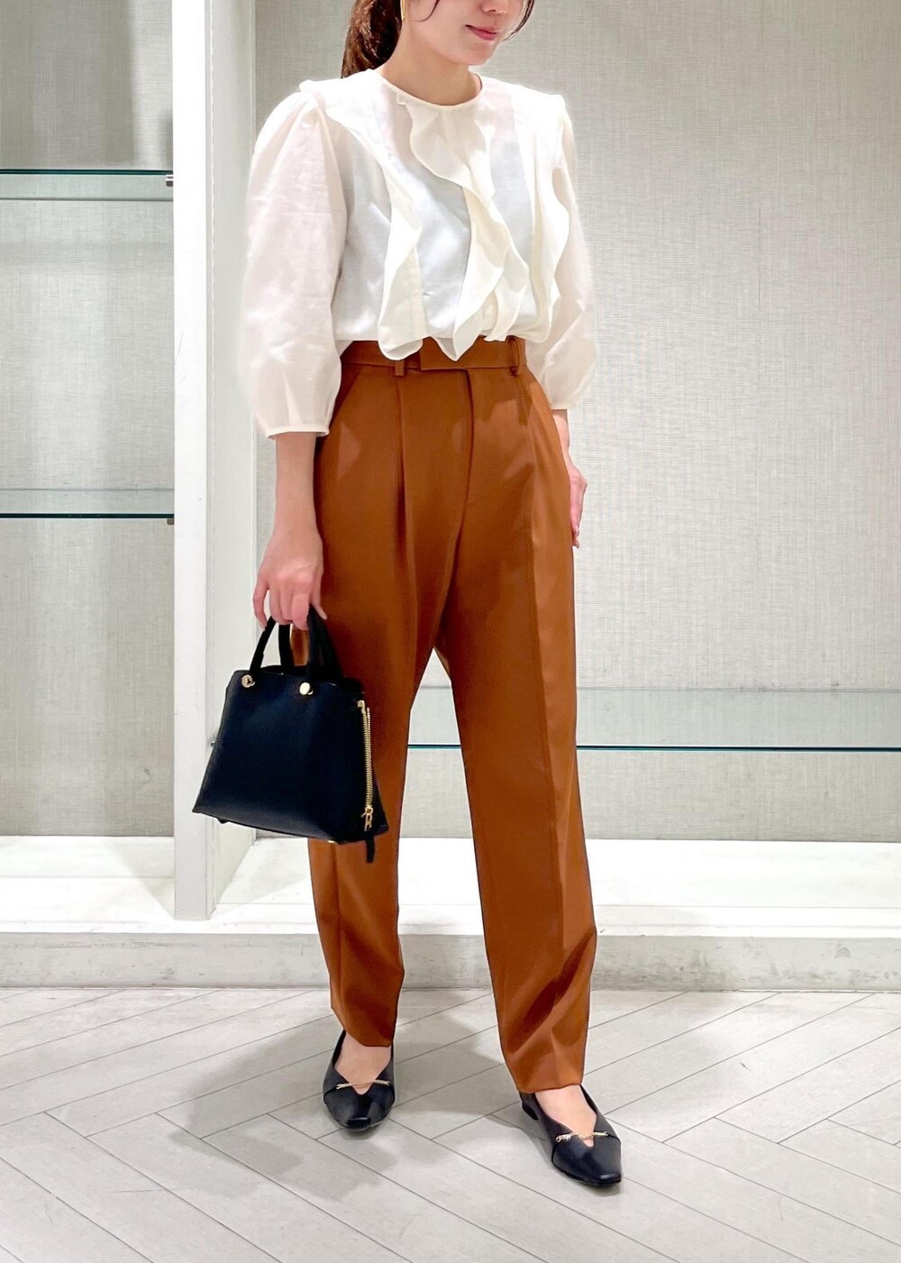 ブラック系のハンドバッグ、ブラック系のパンプス、ホワイト系のシャツ/ブラウスを着用したレディースの秋コーディネートの6枚目の写真