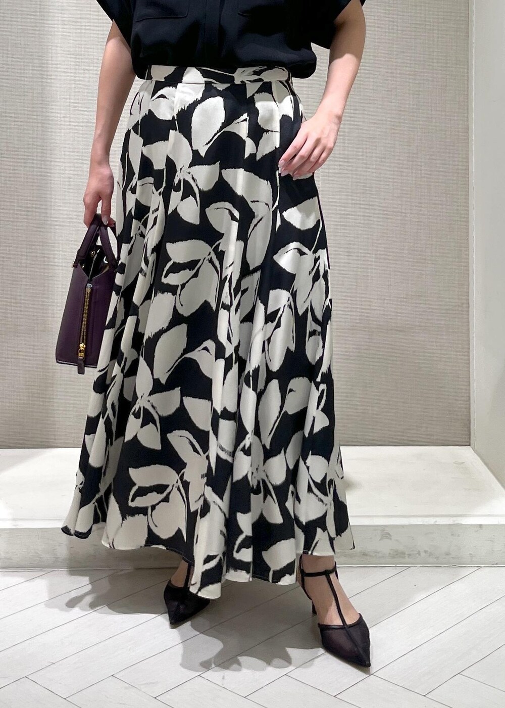 ブラック系のパンプス、パープル系のハンドバッグ、ブラック系のスカートを着用したレディースの秋コーディネートの6枚目の写真