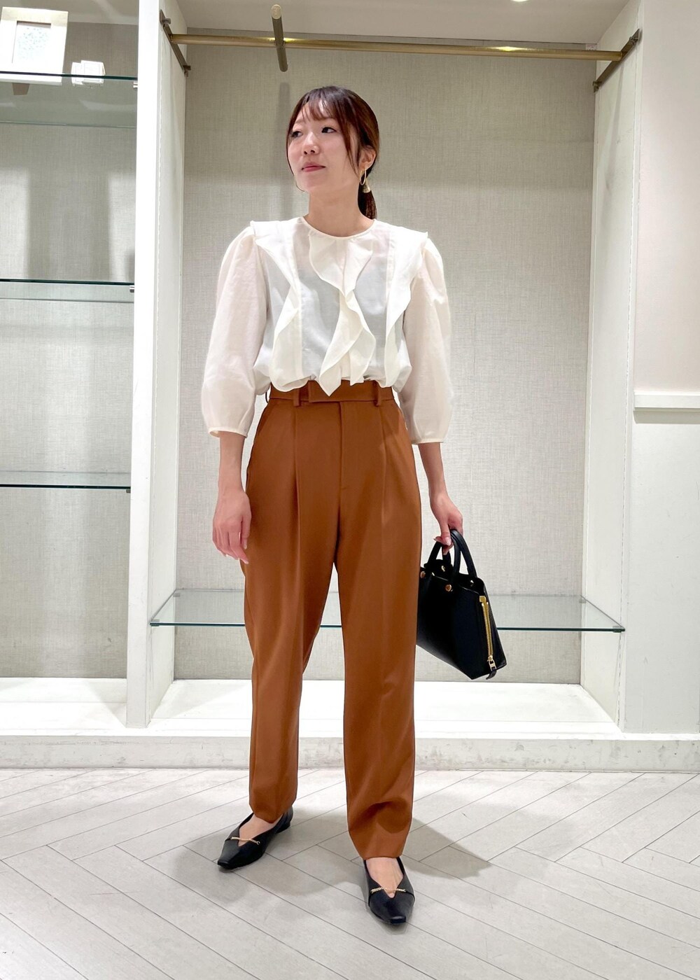 ブラック系のハンドバッグ、ブラック系のパンプス、ホワイト系のシャツ/ブラウスを着用したレディースの秋コーディネートの2枚目の写真