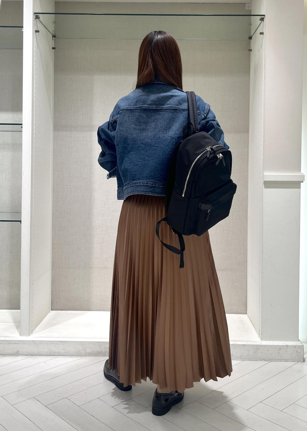 イエロー系のスカート、ブラック系のバックパック/リュック、ブラック系のローファーを着用したレディースの春コーディネートの3枚目の写真