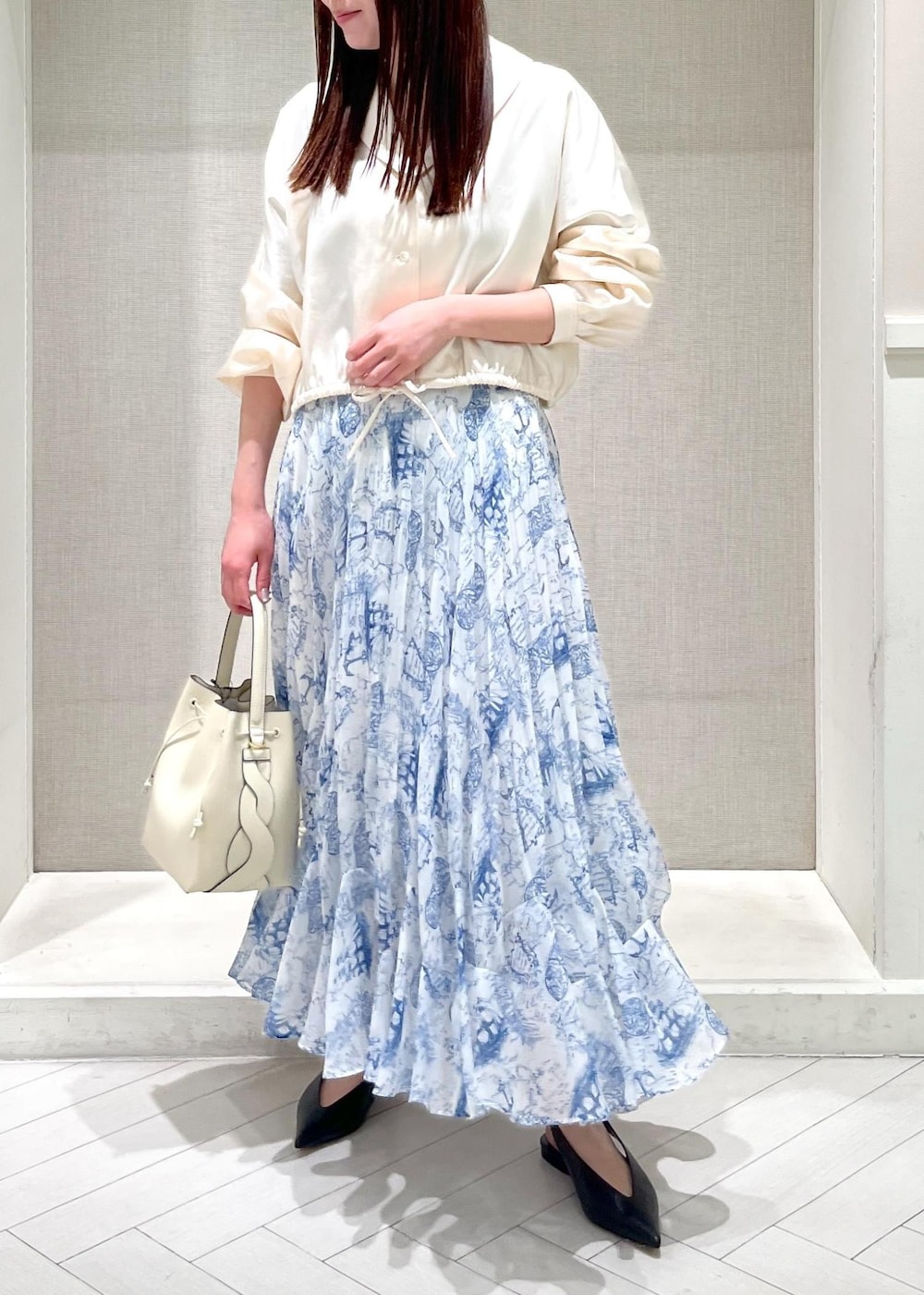 ブラック系のパンプス、ブルー系のスカート、ホワイト系のシャツ/ブラウスを着用したレディースの冬コーディネートの4枚目の写真