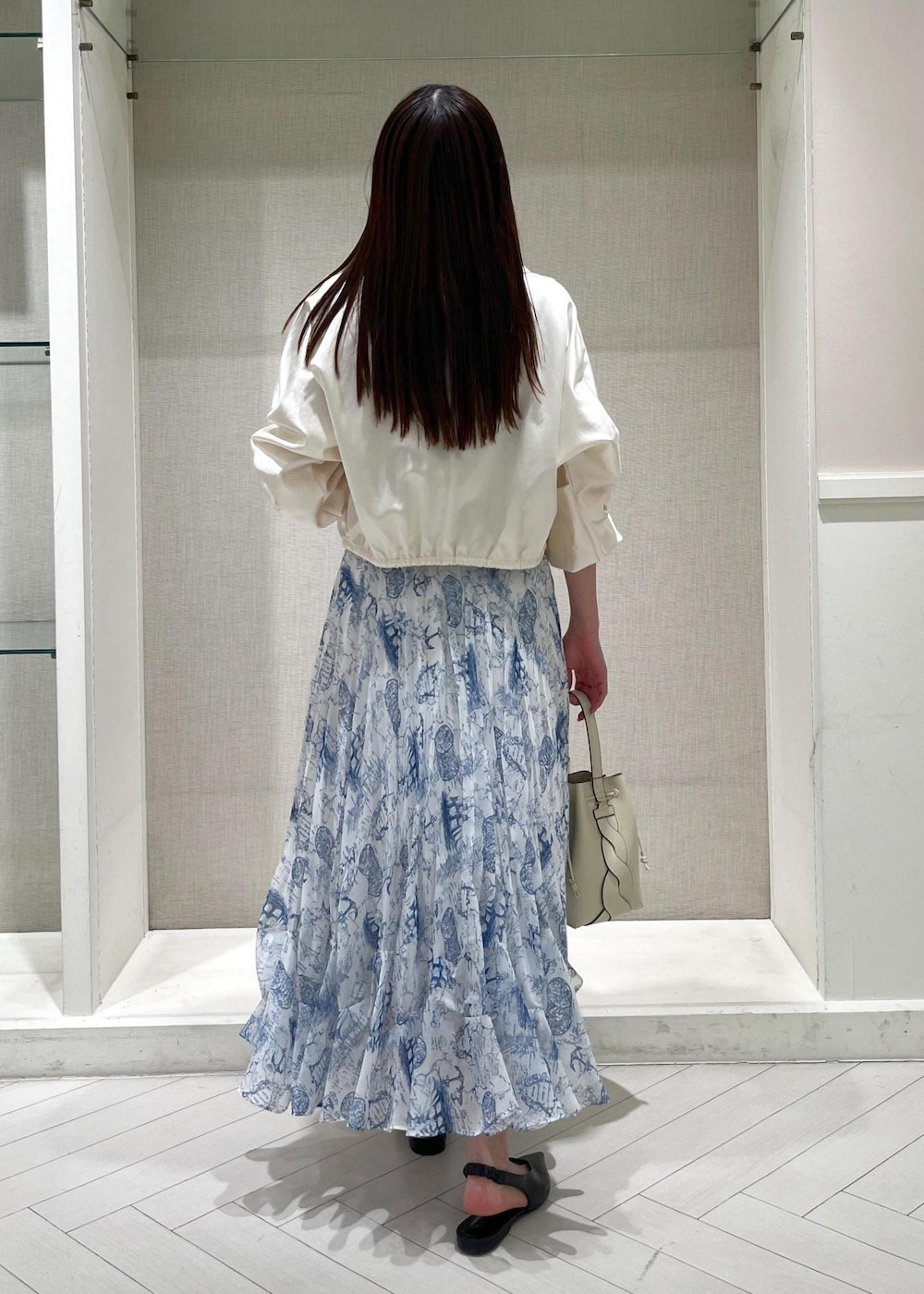 ブラック系のパンプス、ブルー系のスカート、ホワイト系のシャツ/ブラウスを着用したレディースの冬コーディネートの3枚目の写真