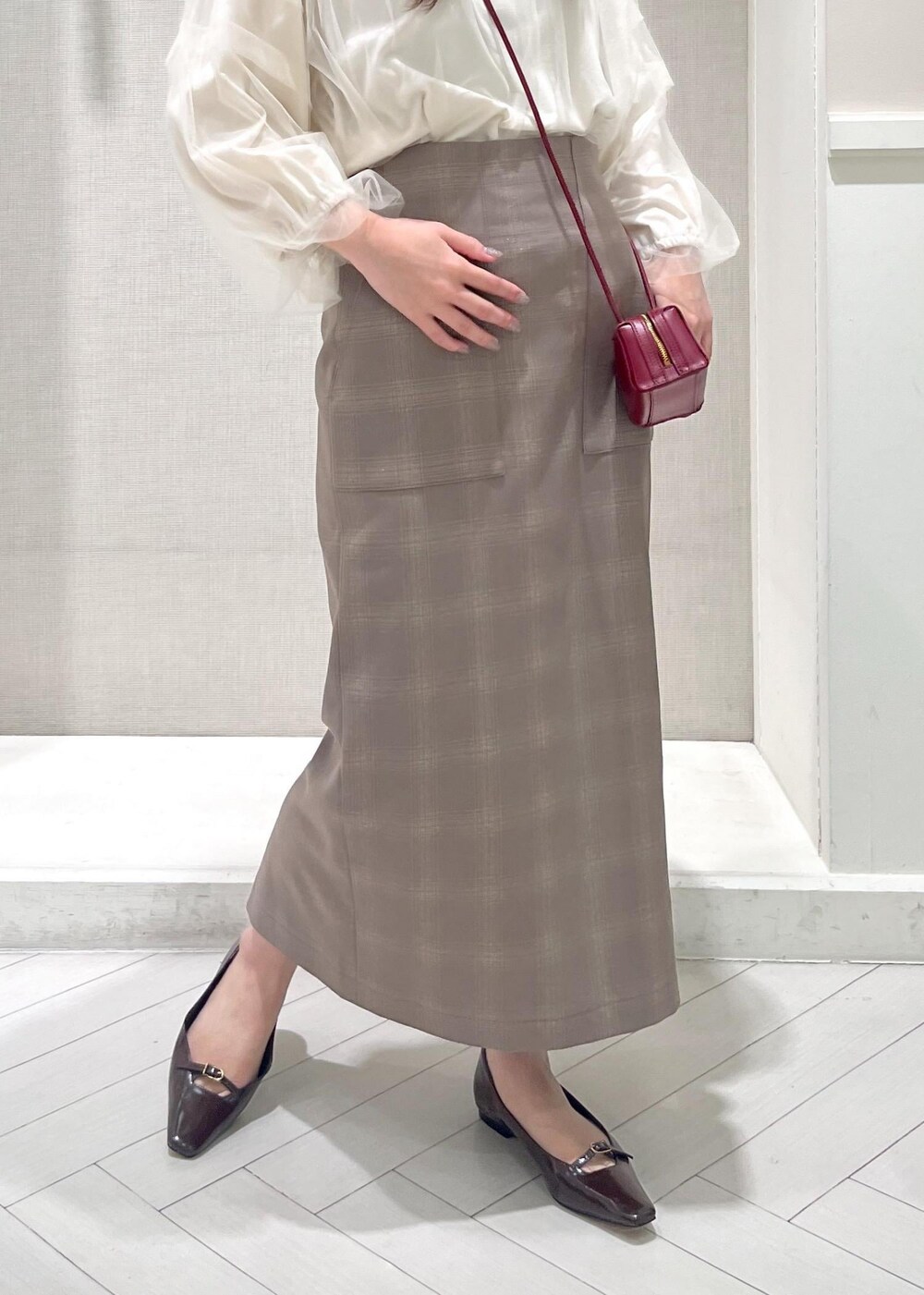 レッド系のショルダーバッグ、ブラウン系のパンプス、ベージュ系のスカートを着用したレディースの秋コーディネートの6枚目の写真
