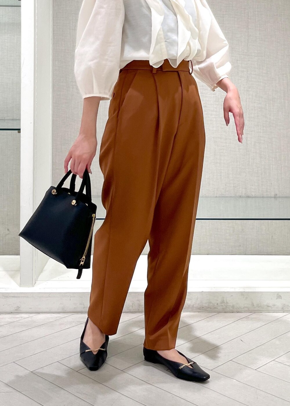 ブラック系のハンドバッグ、ブラック系のパンプス、ホワイト系のシャツ/ブラウスを着用したレディースの秋コーディネートの7枚目の写真