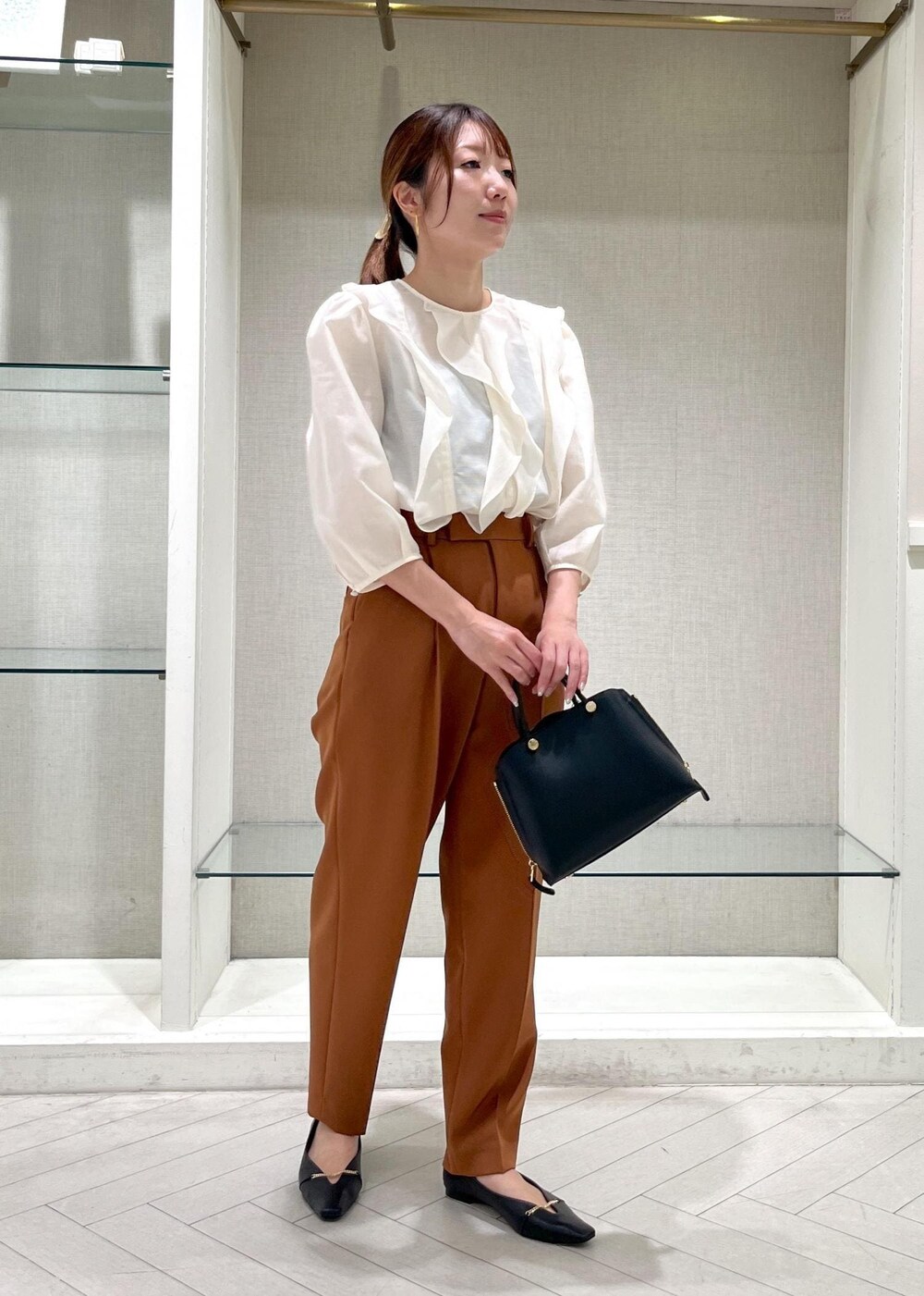 ブラック系のハンドバッグ、ブラック系のパンプス、ホワイト系のシャツ/ブラウスを着用したレディースの秋コーディネートの3枚目の写真