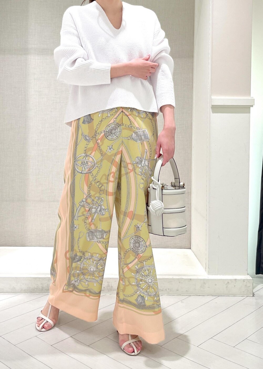 ホワイト系のハンドバッグ、ホワイト系のニット/セーター、イエロー系のその他パンツを着用したレディースの春コーディネートの4枚目の写真