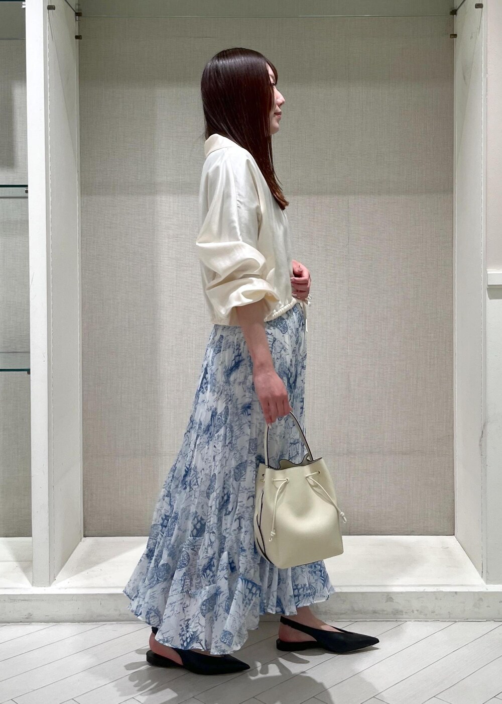 ブラック系のパンプス、ブルー系のスカート、ホワイト系のシャツ/ブラウスを着用したレディースの冬コーディネートの2枚目の写真