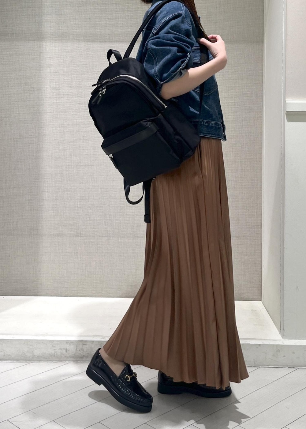 イエロー系のスカート、ブラック系のバックパック/リュック、ブラック系のローファーを着用したレディースの春コーディネートの7枚目の写真