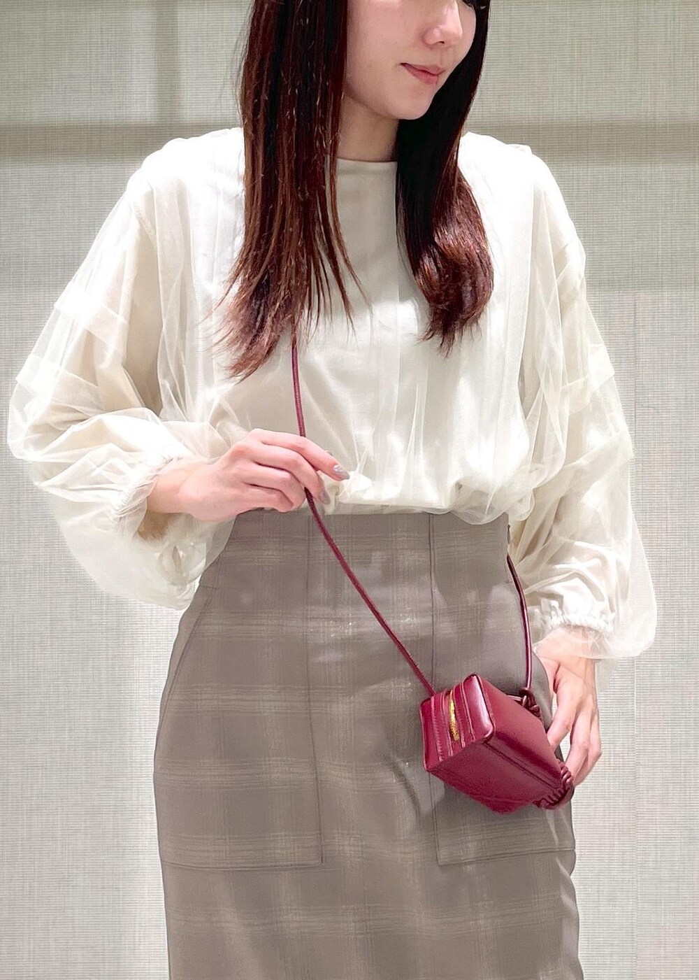 レッド系のショルダーバッグ、ブラウン系のパンプス、ベージュ系のスカートを着用したレディースの秋コーディネートの5枚目の写真