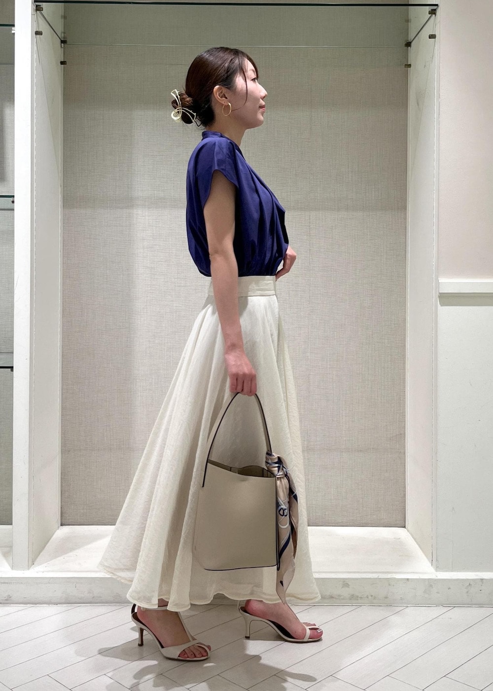 ホワイト系のサンダル、ホワイト系のスカート、ブルー系のシャツ/ブラウスを着用したレディースの春コーディネートの2枚目の写真