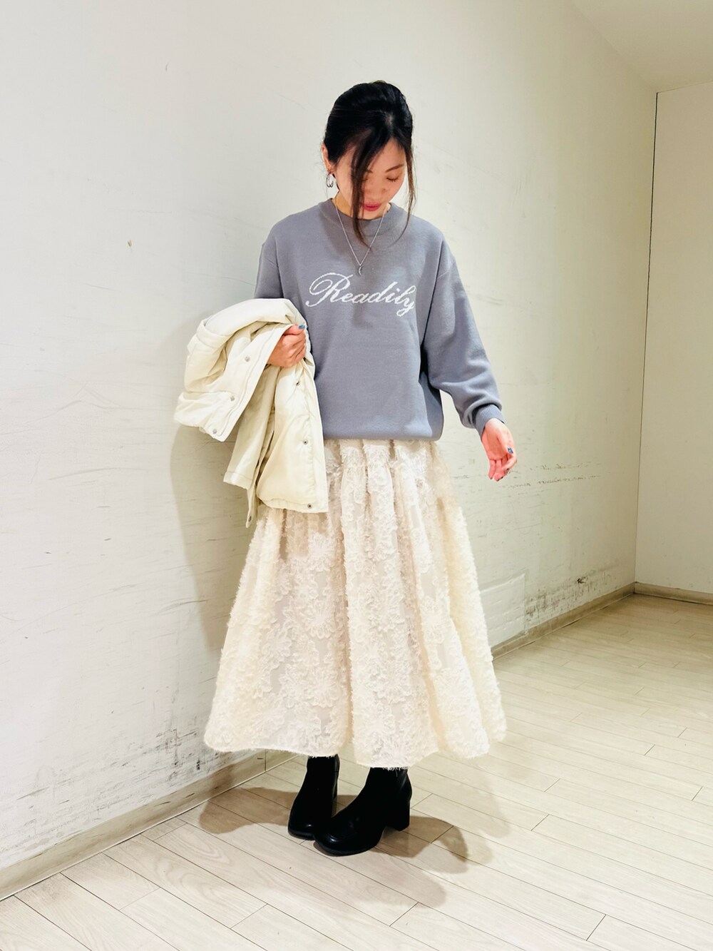 ホワイト系のノーカラージャケット、グレー系のニット/セーター、ホワイト系のスカートを着用したレディースの冬コーディネートの2枚目の写真