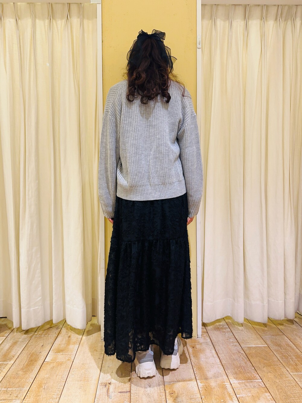 ホワイト系のTシャツ/カットソー、グレー系のカーディガン/ボレロ、ブラック系のスカートを着用したレディースの冬コーディネートの2枚目の写真