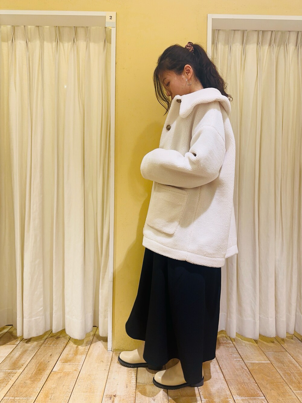 ホワイト系のノーカラージャケット、ベージュ系のニット/セーター、ブラック系のワンピースを着用したレディースの冬コーディネートの3枚目の写真