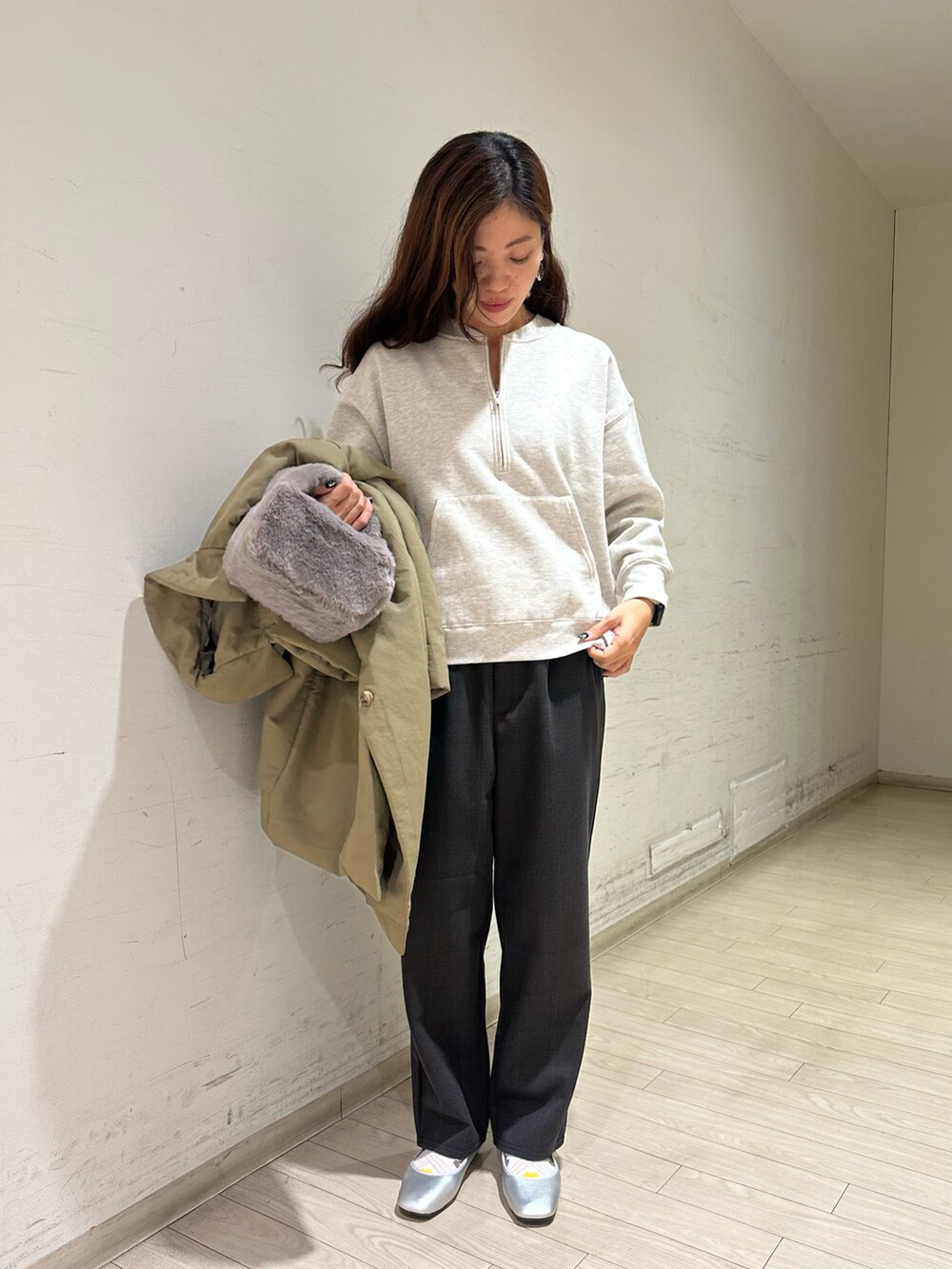 グリーン系のステンカラーコート、グレー系のTシャツ/カットソー、グレー系のハンドバッグを着用したレディースの秋コーディネートの3枚目の写真