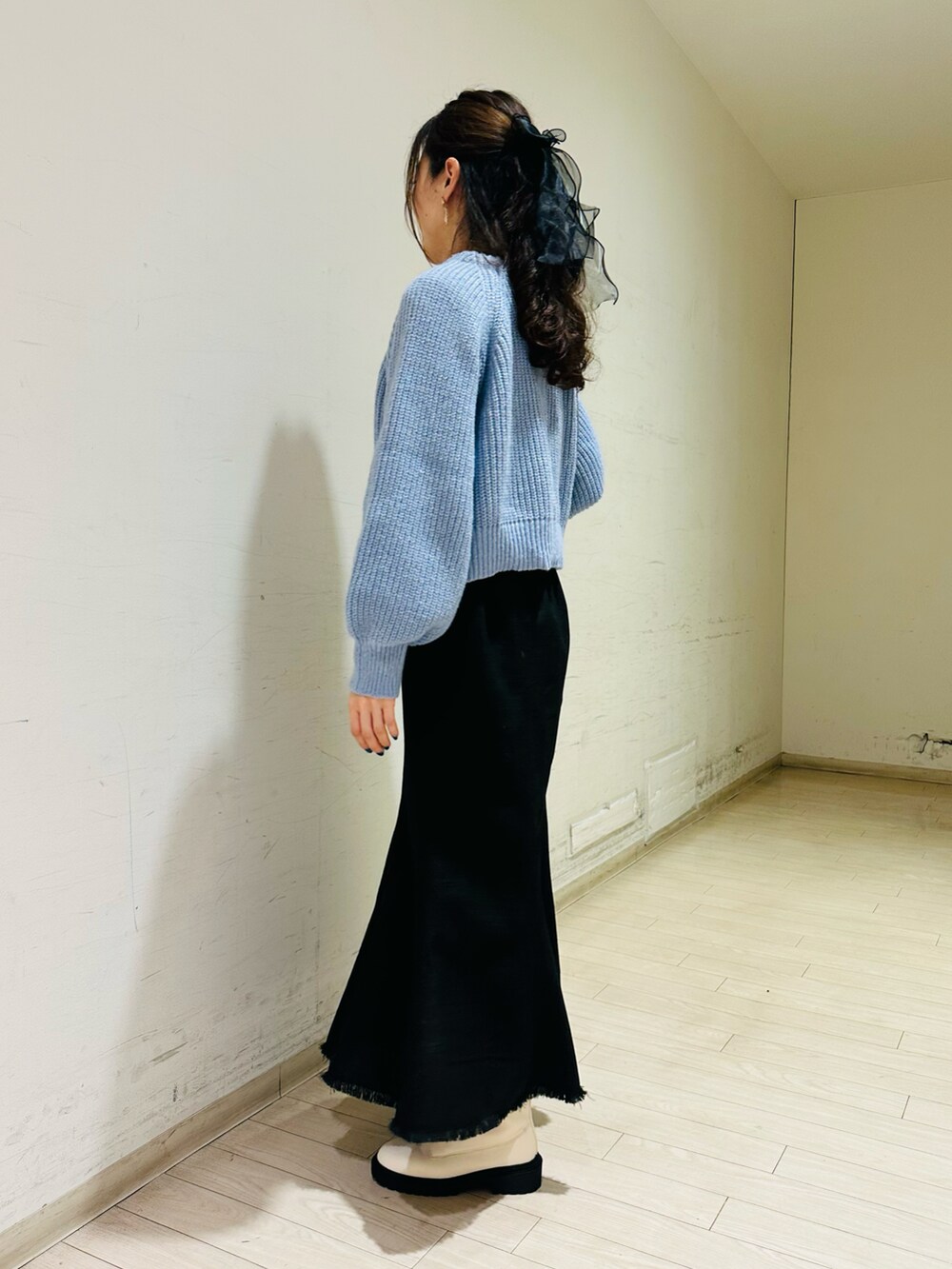 ブルー系のカーディガン/ボレロ、ホワイト系のニット/セーター、ブラック系のスカートを着用したレディースの冬コーディネートの2枚目の写真