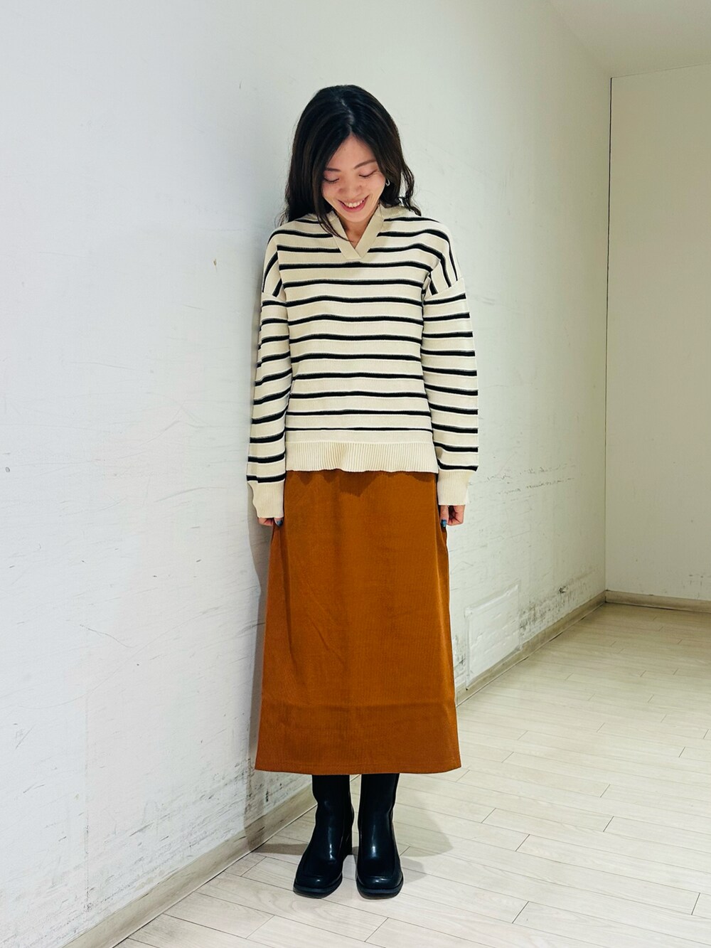 グリーン系のブルゾン、ホワイト系のニット/セーター、イエロー系のスカートを着用したレディースの冬コーディネートの2枚目の写真