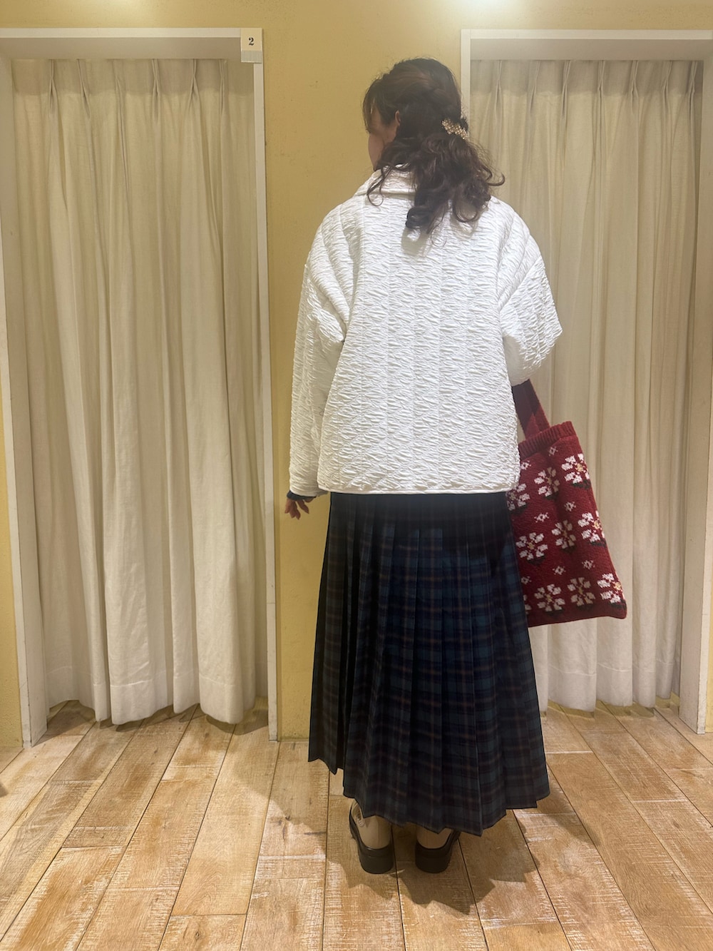 ホワイト系のノーカラージャケット、ブルー系のニット/セーター、グリーン系のスカートを着用したレディースの秋コーディネートの2枚目の写真