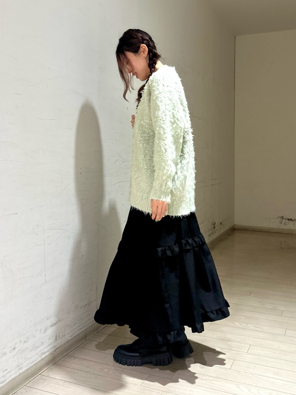 グリーン系のトップス、ホワイト系のハンドバッグ、ブラック系のワンピースを着用したレディースの秋コーディネートの2枚目の写真