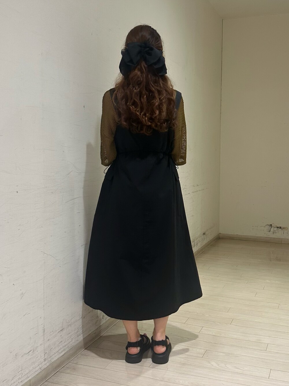 グリーン系のニット/セーター、ホワイト系のハンドバッグ、ブラック系のドレスシューズを着用したレディースの春コーディネートの2枚目の写真