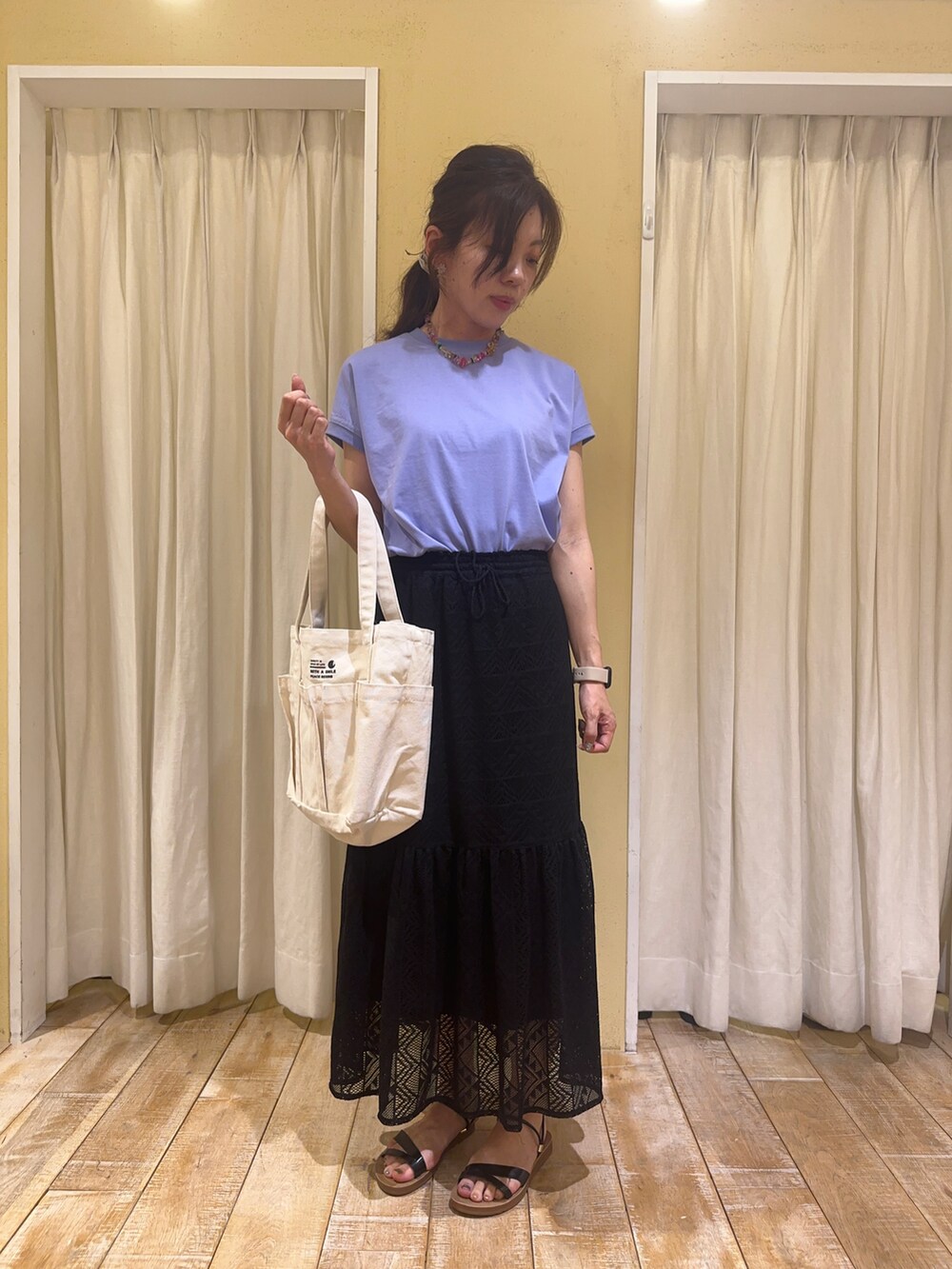 ブラック系のスカート、ホワイト系のハンドバッグ、ブラック系のサンダルを着用したレディースの春コーディネートの3枚目の写真