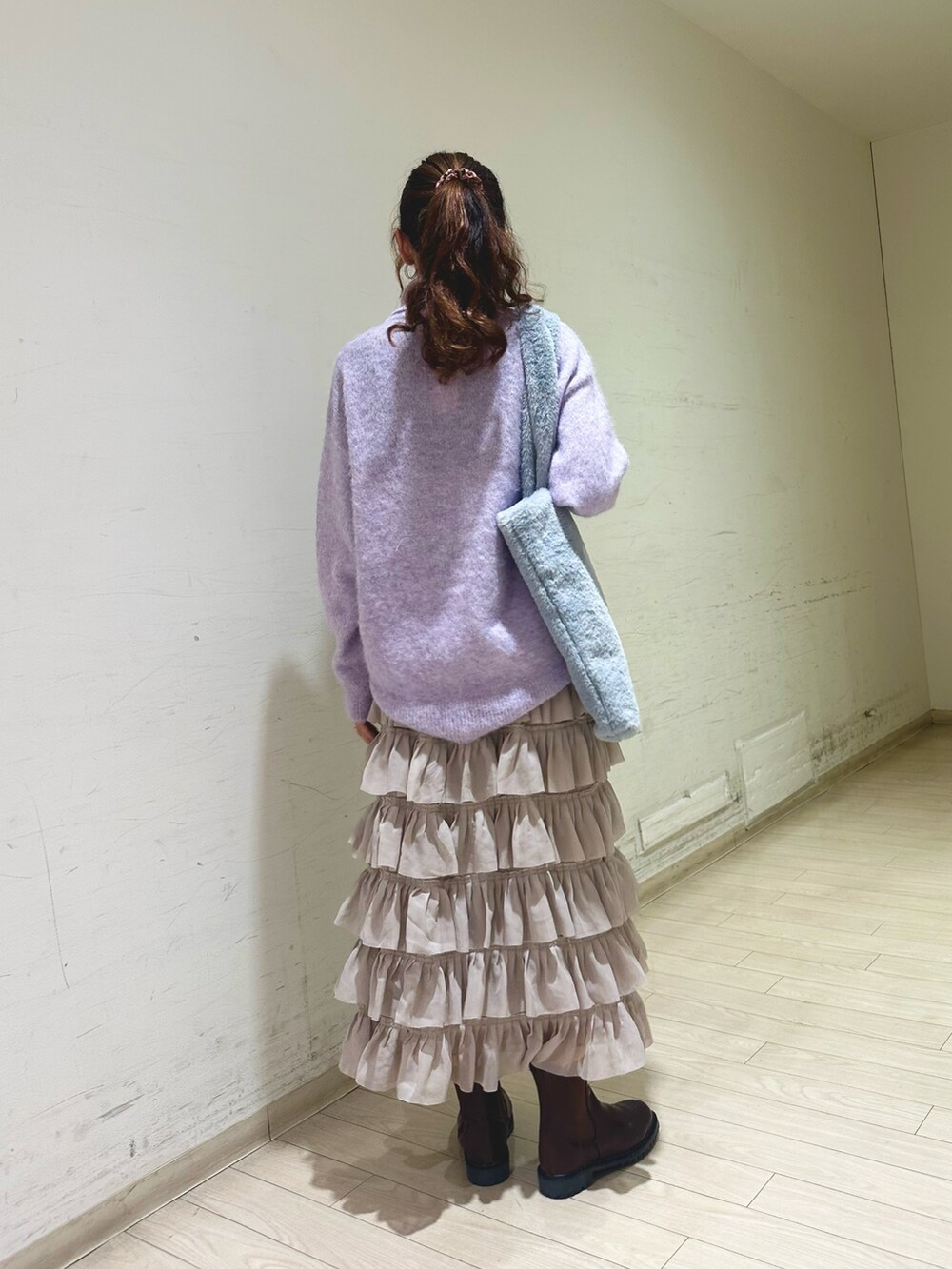 パープル系のニット/セーター、グレー系のハンドバッグ、ベージュ系のスカートを着用したレディースの冬コーディネートの2枚目の写真